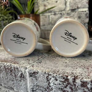 May include: Two white ceramic mugs with a Disney logo and the text "Dishwasher and Microwave Safe" on the bottom. The mugs are made in China.