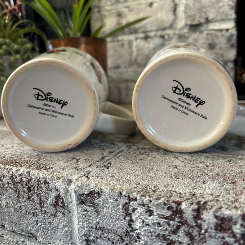 May include: Two white ceramic mugs with a Disney logo and the text "Dishwasher and Microwave Safe" on the bottom. The mugs are made in China.