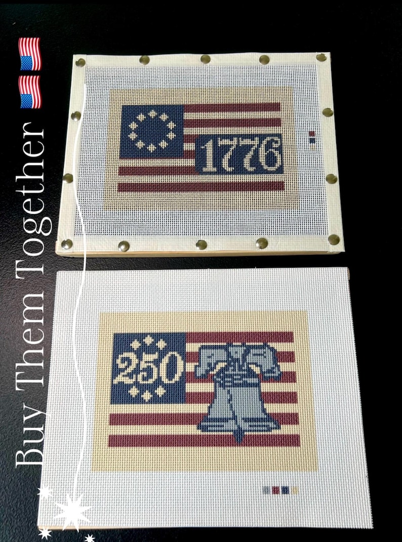 May include: Two needlepoint canvases featuring patriotic designs. One displays the American flag with "1776" and the other shows the Liberty Bell with "250". Both have a cream-colored background and are framed with wooden borders.
