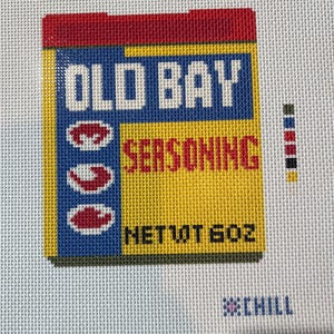 May include: Needlepoint of an Old Bay Seasoning box. The box is yellow, blue, and red with the words "OLD BAY SEASONING" in white. The net weight is 6 oz. The needlepoint is on a white background.