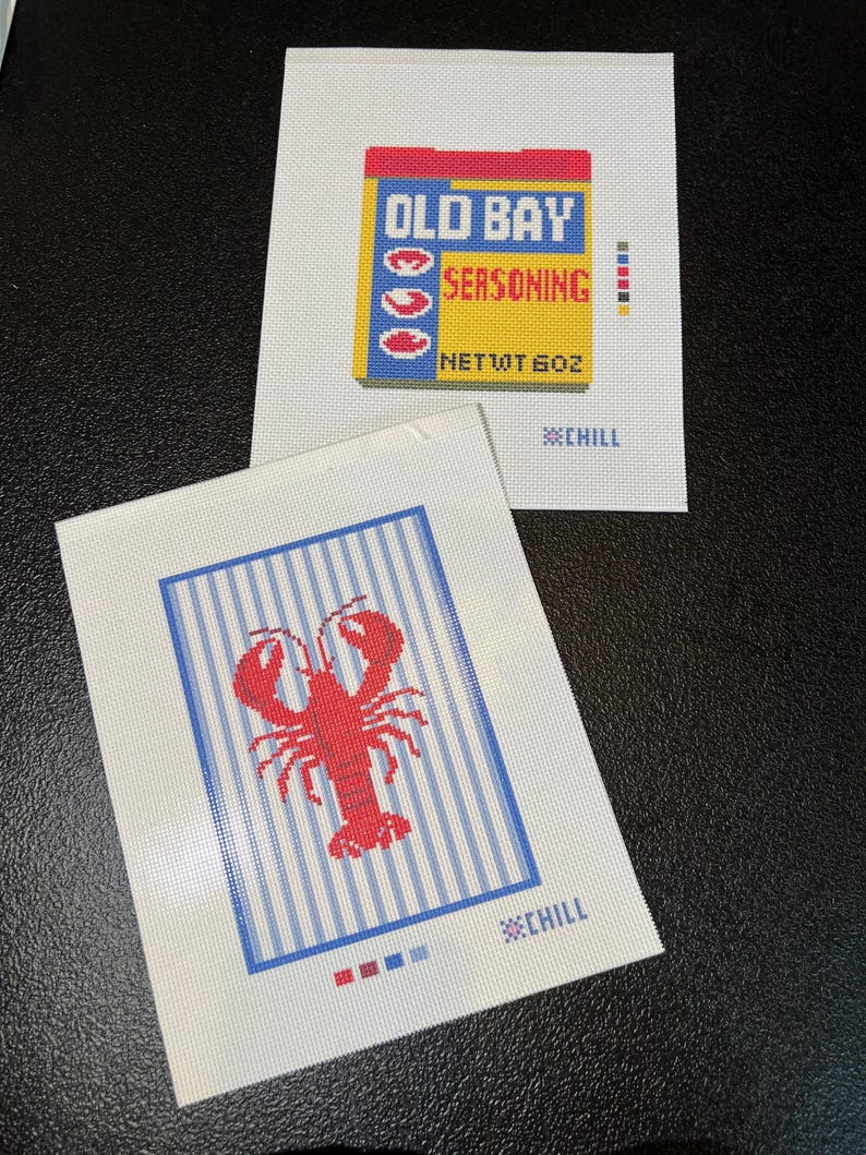 May include: Two needlepoint canvases. One features the Old Bay seasoning box with text and a net weight of 6 oz. The other canvas has a red lobster over blue and white stripes. Both have the word "CHILL".