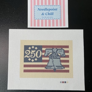 May include: Needlepoint canvas featuring a patriotic design with the Liberty Bell and the number "250" on a flag. The canvas is white with a rectangular design in shades of red, blue, and beige. The text "Needlepoint & Chill" is also visible.