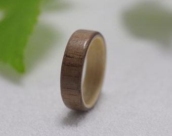 May include: A wooden ring with a light brown finish. The ring has a natural wood grain pattern and a smooth surface.