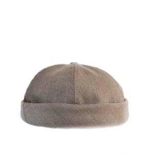 Könnte beinhalten: Eine taupefarbene Mütze mit umgeschlagenem Rand. Der Hut besteht aus einem strukturierten Stoff und hat eine Naht in der Mitte. Dieser lässige Hut eignet sich für verschiedene Outfits und Wetterbedingungen.