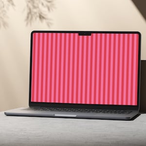 Op de afbeelding: Een donkergrijze laptop met een dunne rand en een gecentreerde webcam-inkeping aan de bovenkant van het scherm. Het display toont een levendig verticaal streeppatroon in afwisselende tinten felroze en een diepere, donkerrode kleur.