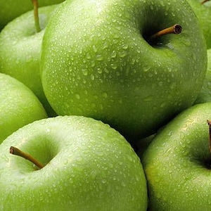 May include: Close-up of several green Granny Smith apples. The apples are covered in water droplets, giving them a fresh appearance. Each apple has a brown stem. The image is well-lit, highlighting the vibrant green color.