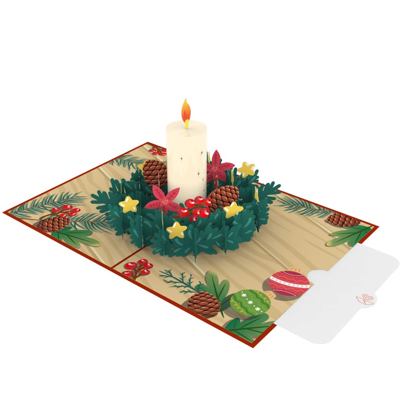 May include: A 3D pop-up card featuring a white candle in a green wreath with red berries, pine cones, and gold stars. The card has a wooden background with a small envelope attached.