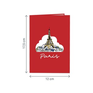 Puede incluir: Una tarjeta roja con una ilustraci&oacute;n emergente de la Torre Eiffel en Par&iacute;s, Francia. La tarjeta mide 12 cm por 17,5 cm y dice "Par&iacute;s" en letras blancas.