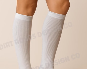 May include: White ribbed knee-high socks. The socks are made of a soft material and have a ribbed texture. The socks are worn on the legs. The text "DIRT ROADS DESIGN CO" is printed on the socks.