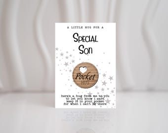 Könnte beinhalten: Eine weiße Karte mit dem Text "A Little Hug For A Special Son" und einem kleinen Holz-Kreis mit dem Text "Pocket Hug" und einem Herz.