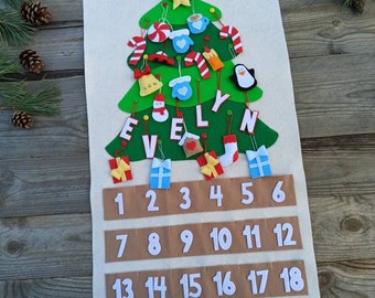 May include: A felt Christmas advent calendar in the shape of a green tree, decorated with ornaments and the name "EVELYN". The calendar has numbered pockets from 1 to 24, with small gift and stocking decorations.