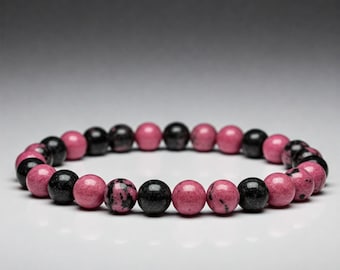 May include: A pink and black beaded bracelet with alternating colors. The beads are round and have a marbled pattern.