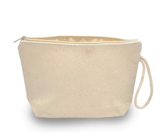 Könnte beinhalten: Eine beigefarbene Kosmetiktasche aus Segeltuch mit gesprenkelter Textur, einem goldfarbenen Metallreißverschluss an der Oberkante und einer passenden beigefarbenen geflochtenen Handschlaufe aus Seil an der rechten Seite der Tasche.