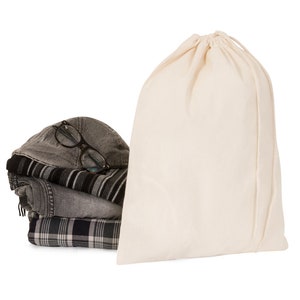 May include: A white cotton drawstring bag with a stack of folded clothing and a pair of glasses on top.