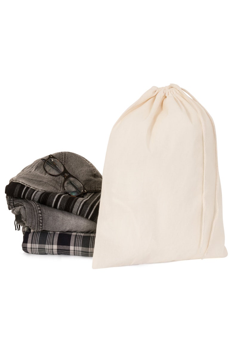 May include: A white cotton drawstring bag with a stack of folded clothing and a pair of glasses on top.
