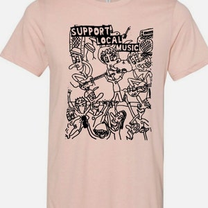 Peut inclure: Un t-shirt rose avec une illustration en noir et blanc d'un groupe de musique jouant. Le texte "SUPPORT LOCAL MUSIC" est imprimé sur le t-shirt.