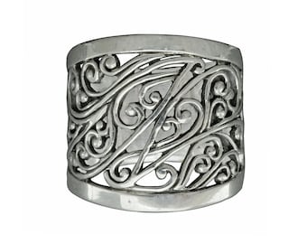 Puede incluir: Un anillo de plata con una banda ancha que presenta un diseño delicado e intrincado de líneas en espiral interconectadas y pequeñas cuentas.