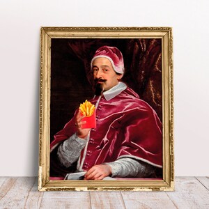 Op de afbeelding: Een schilderij van een man in een rode mantel die een rood doosje frietjes vasthoudt. De man draagt een hoed en heeft een baard. Het schilderij is in een gouden lijst.