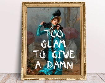 May include: A framed painting of a woman in a blue dress and a black hat. The woman is standing in a forest with trees and a red umbrella. The text "TOO GLAM TO GIVE A DAMN" is written in white paint over the image.