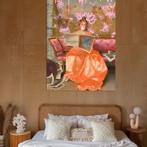 May include: A woman in a long orange dress sits on a pink and gold couch, reading a book. The background is a painting with pink graffiti.