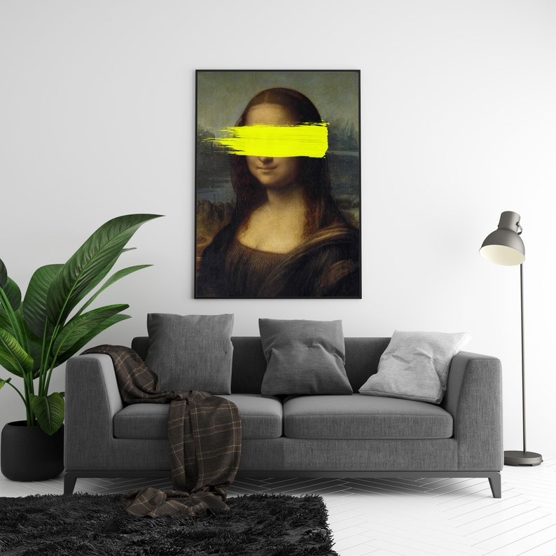 May include: A framed print of the Mona Lisa painting with a yellow paint stroke covering her eyes.