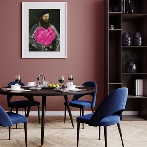 May include: A round dining table with a dark wood top and black metal legs. Four blue velvet chairs surround the table. A framed portrait of a man holding a pink flower bouquet hangs on the wall behind the table. A tall black bookshelf with shelves filled with books and decorative objects is in the background.