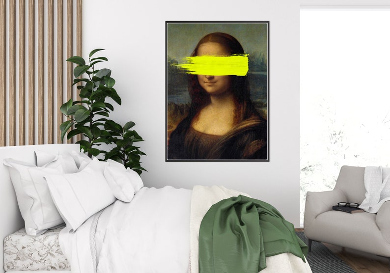May include: A framed print of the Mona Lisa painting with a yellow paint stroke covering her eyes.