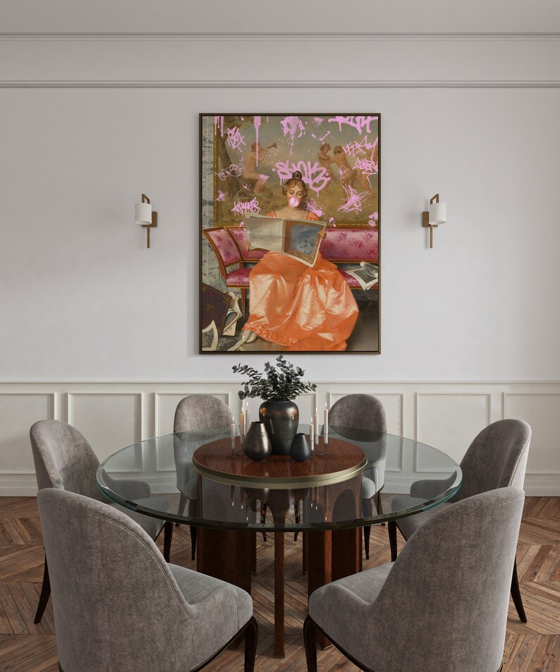 May include: A round glass dining table with a wood top and six gray upholstered chairs. A painting of a woman in a long orange dress with pink graffiti on the wall behind the table.