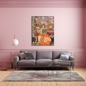 May include: A painting of a woman in a long orange dress sitting on a couch and reading a book. The painting is surrounded by pink graffiti.