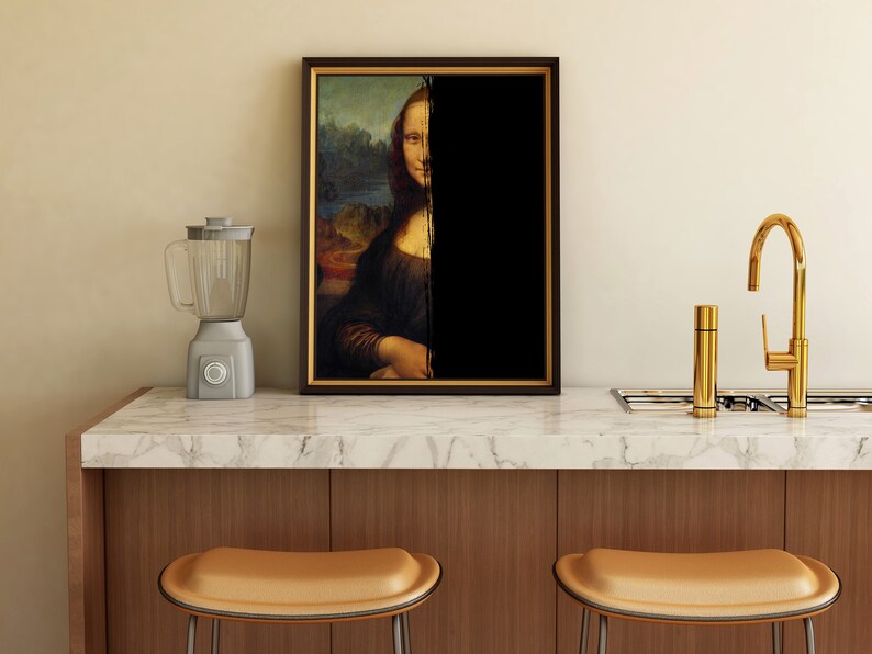 May include: A framed print of the Mona Lisa, with half of the image obscured by black. A grey blender sits to the left, and a gold tap is on the right. The artwork is displayed on a marble countertop.