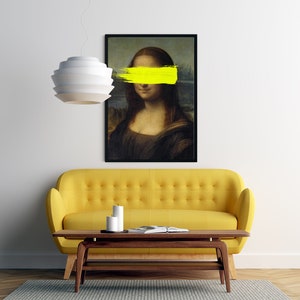 May include: A yellow sofa with a coffee table in front of it. A black framed print of the Mona Lisa with a yellow stripe painted over her eyes hangs on the wall above the sofa.
