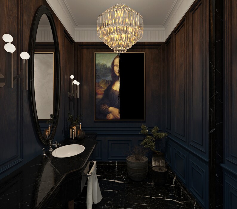 May include: A stylish bathroom with dark wood paneling and a black marble countertop. The room features a large oval mirror, a crystal chandelier, and a framed painting of the Mona Lisa. A small potted plant adds a touch of greenery.