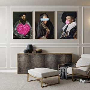 May include: Three framed portraits of people in historical clothing. The person in the left portrait is holding a pink flower bouquet. The person in the middle portrait has a blue stripe over their eyes. The person in the right portrait has a pink bubble in their mouth.