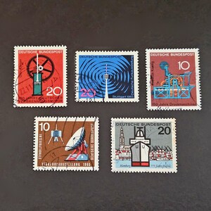 Könnte beinhalten: Fünf deutsche Briefmarken im Vintage-Stil. Die Briefmarken zeigen Illustrationen einer Dampfmaschine, eines Funkturms, einer Druckmaschine, einer Satellitenschüssel und eines Schiffs. Jede Briefmarke trägt die Aufschrift "DEUTSCHE BUNDESPOST".
