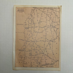 May include: A vintage Rand McNally map of Mississippi, featuring a network of roads and railways. The map is printed on aged paper with the state's name prominently displayed. The Gulf of Mexico is visible at the bottom.