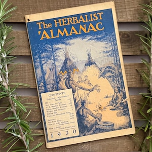May include: Vintage 1930 "The Herbalist Almanac" book with a blue cover featuring illustrations of Native American life. The cover art includes teepees, figures around a fire, and the text "The Herbalist Almanac." The book's contents are listed on the inside cover.