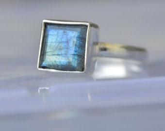 May include: A silver ring with a square-shaped blue labradorite gemstone.