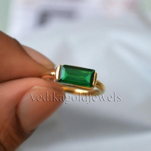 Puede incluir: Un anillo de oro con una piedra rectangular verde esmeralda. El anillo es simple y elegante, perfecto para el uso diario.