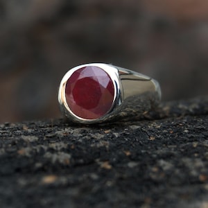 Peut inclure: Une bague en argent avec une grosse pierre précieuse de rubis rouge ronde.