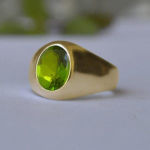 May include: A gold ring with a large, oval-shaped green gemstone.