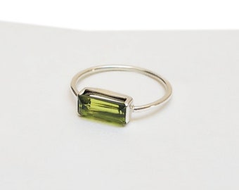 May include: A silver ring featuring a rectangular green gemstone. The ring is simple and elegant.