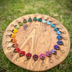 Peut inclure: Un assortiment d'boucles d'oreilles en crochet arc-en-ciel présenté sur une surface en bois. Les boucles d'oreilles sont faites de fil coloré et présentent un accent de perle en bois.