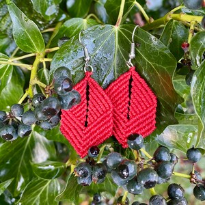 Könnte beinhalten: Ein Paar rote gehäkelte Ohrringe mit geometrischem Muster. Die Ohrringe hängen an silbernen Haken.