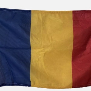 May include: A blue, yellow, and red flag with a white border and grommets. The flag is made of fabric and is hanging from a pole.