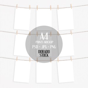 May include: Eight blank A4 prints hanging on a clothesline with wooden clothespins against a white background. The text "A4 PRINTS MOCKUP PSD + JPG + PNG DORADO STOCK" is in the center of the image.