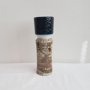 Puede incluir: Un jarrón de cerámica con un cuerpo texturizado marrón y blanco y una parte superior azul oscuro.
