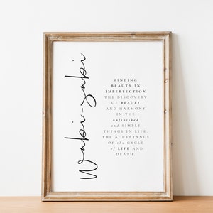 May include: A framed print with the text "Wabi-sabi" written vertically on the left side of the frame. The text on the right side of the frame reads "Finding beauty in imperfection, the discovery of beauty and harmony in the unfinished and simple things in life, the acceptance of the cycle of life and death."