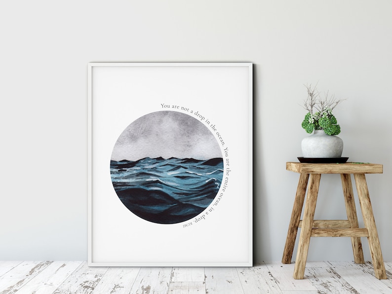 May include: A white framed print with a blue and gray watercolor illustration of ocean waves in a circle. The text "You are not a drop in the ocean. You are the entire ocean, in a drop" is written around the circle.