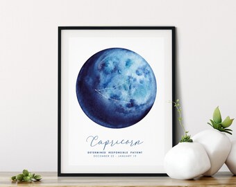 May include: A framed wall art print featuring a watercolour blue moon with a white Capricorn constellation overlay. Below the moon, the text reads Capricorn, Determined Responsible Patient, and the date range December 22 - January 19 in blue.