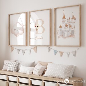 May include: Three framed watercolour prints with a light pink and brown colour scheme. The prints feature a cloud with a face, a letter B with floral accents, and a castle. The letter B print includes the name "Brooke".